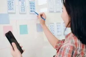 mulher desenhando em quadro branco um modelo de navegação de aplicativo